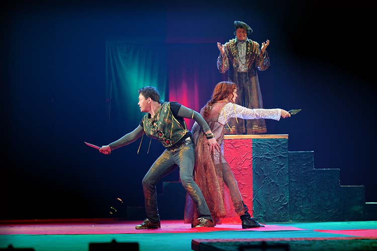 舞台の上で中世ヨーロッパのコスチュームを身に着け芝居をする俳優たち